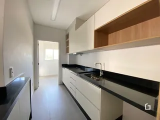 Vista da cozinha moderna com armários brancos e bancadas escuras.