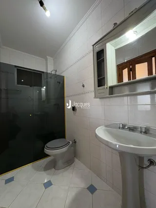 Banheiro com revestimento cerâmico nas paredes e piso de azulejos claros.