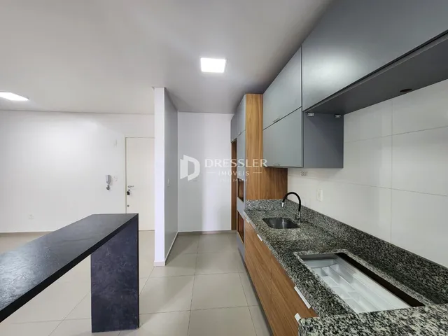 Vista interna de uma cozinha moderna com armários cinzas e bancada de granito.