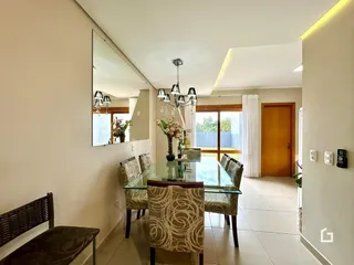 Uma sala de jantar com mesa de vidro e cadeiras em um imóvel no Brasil.