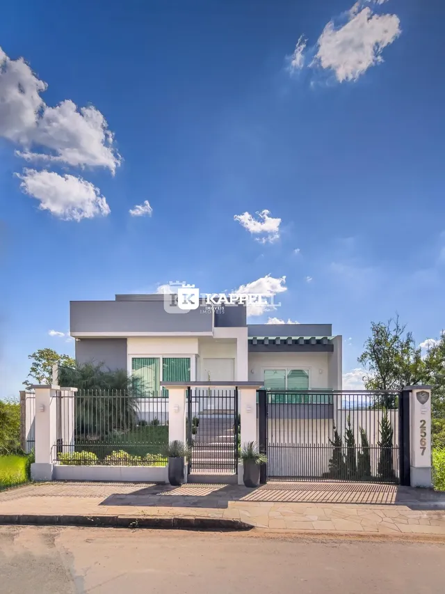 Foto da fachada de uma casa moderna em Lajeado, Brasil, com portão e paisagismo.