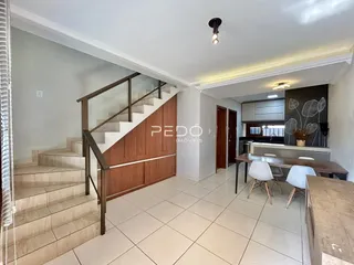 Vista de uma área interna com escadaria e cozinha.