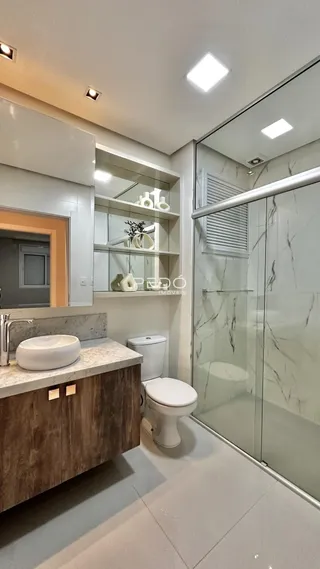 Banheiro moderno com box de vidro e bancada de madeira.