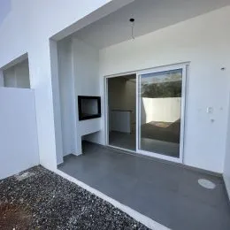 Ambiente interno com paredes brancas e piso cinza, com porta de vidro.