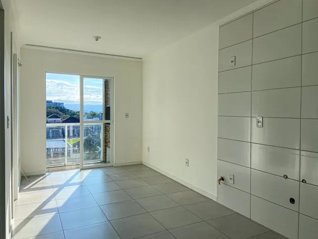 Uma sala ampla com piso de cerâmica e porta de vidro que oferece vista para a paisagem.