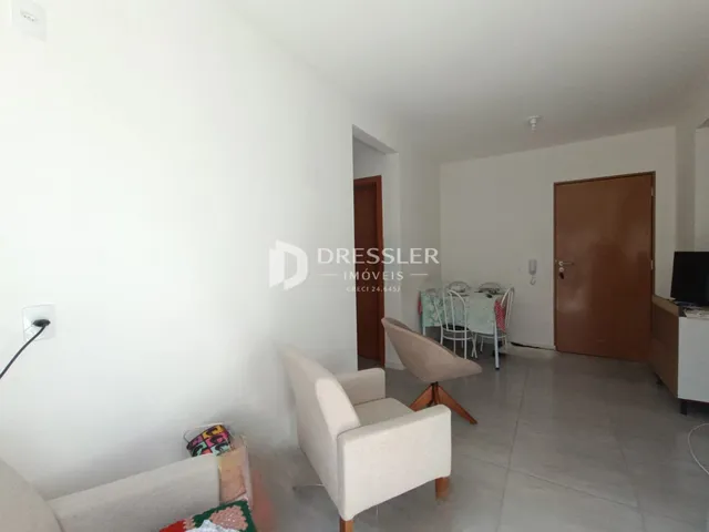 Sala de estar com paredes brancas e piso de cerâmica.