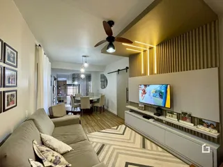 Sala de estar com sofá e televisão em um ambiente claro.