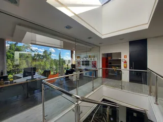 Vista interna de um imóvel com guarda-corpo de vidro e vista para o exterior.