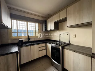 Foto interna de uma cozinha com armários de madeira clara e bancadas escuras.