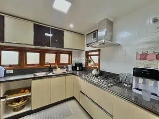 A cozinha apresenta armários de madeira e bancadas escuras.