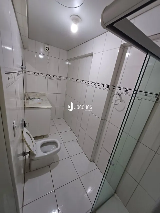 Banheiro com revestimento de cerâmica branca nas paredes e piso.