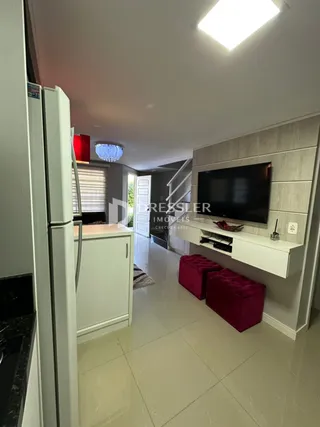 Sala de estar com televisão e armário branco em um imóvel.
