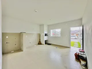 Ambiente interno de uma sala ampla com paredes brancas e piso claro.