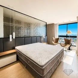 Quarto com cama grande e piso de madeira clara em um imóvel.
