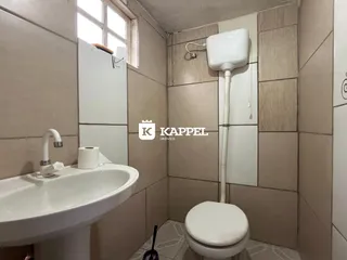 Banheiro com pia e vaso sanitário revestido em azulejos.