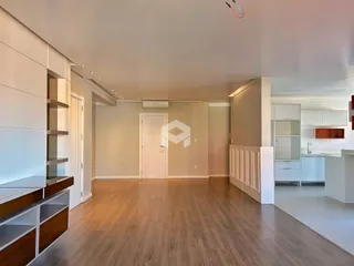 Sala de estar ampla com piso de madeira clara e paredes claras.