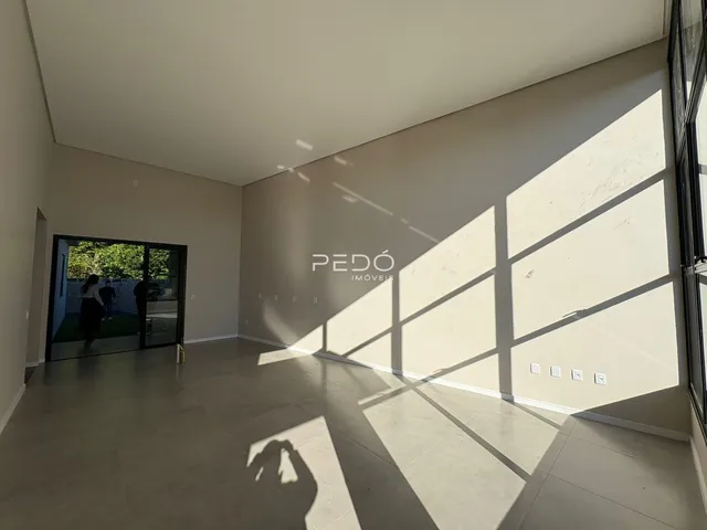 Ambiente interno de uma sala ampla com piso claro e luz natural.