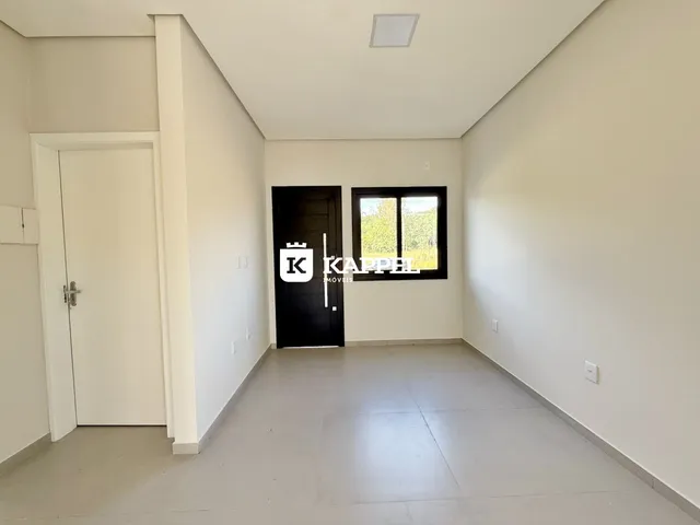 Hall de entrada com portas brancas e uma janela no fundo.