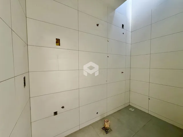 Vista interna de um cômodo com paredes brancas e piso de concreto.