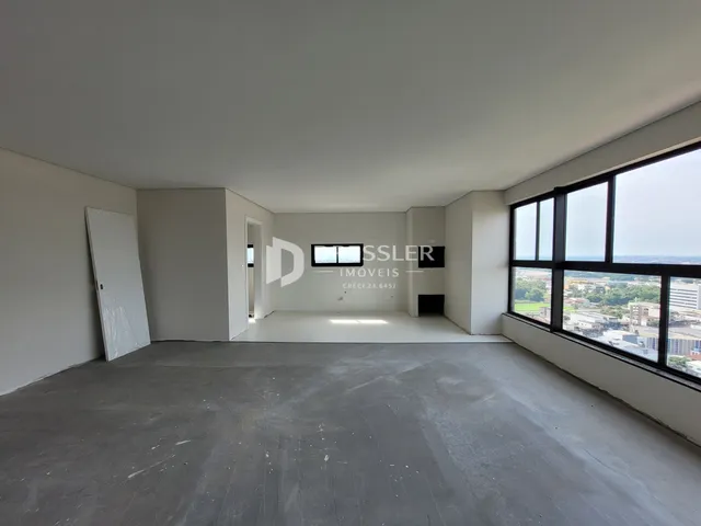 Espaço interno vazio com piso de concreto e grande janela.