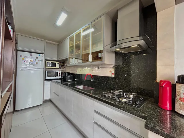 Foto de uma cozinha moderna com armários brancos e bancada escura.