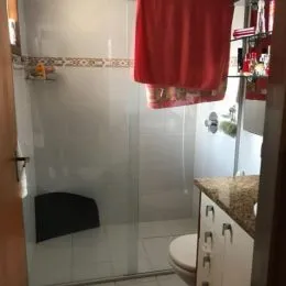 Foto de um banheiro com revestimento de azulejos brancos e box de vidro.