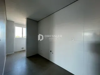 Vista interna de um ambiente com paredes brancas e piso cinza.