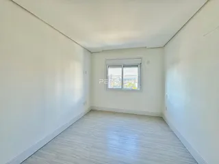 Ambiente interno de uma sala com piso claro e janela com vista.