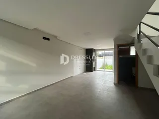 Hall de entrada com paredes brancas e piso de concreto.