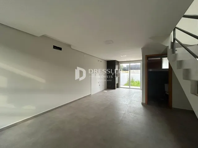 Hall de entrada com paredes brancas e piso de concreto.