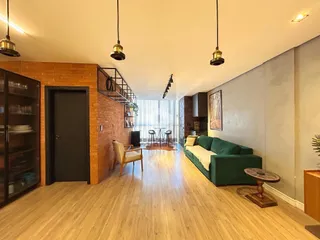 Sala de estar com piso de madeira e parede de tijolos expostos.