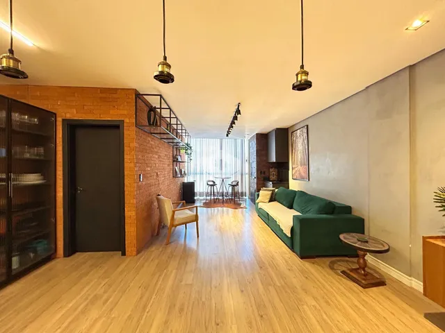 Sala de estar com piso de madeira e parede de tijolos expostos.