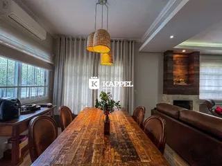 Foto de uma sala de jantar com mesa de madeira escura e cortinas claras.