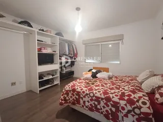 Quarto com cama e estantes brancas em um imóvel.