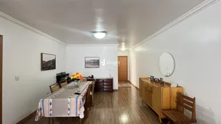 Sala de estar com piso de madeira e mesa de jantar.