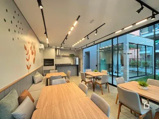 Sala de jantar com mesas de madeira e grandes janelas de vidro.