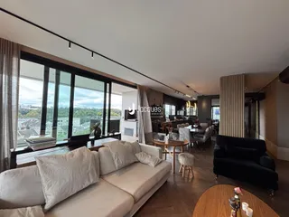 Sala de estar ampla com grandes janelas que oferecem uma vista externa.
