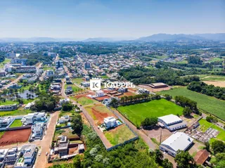 Vista aérea de uma área residencial com campos agrícolas e construções em Lajeado.