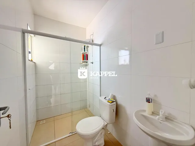 Banheiro com piso de cerâmica e box de vidro.