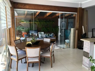 Vista de uma sala de jantar com mesa de madeira e portas de vidro que dão acesso a um jardim.