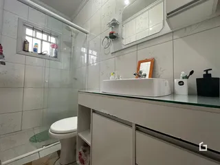 Um banheiro com revestimento de cerâmica e box de vidro.