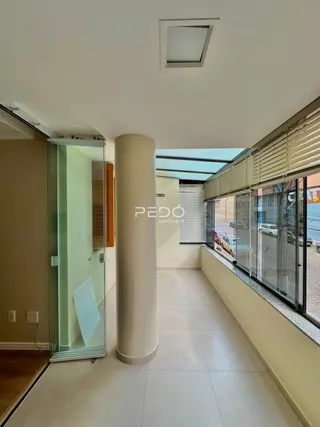 Vista do interior de um imóvel com coluna e portas de vidro.