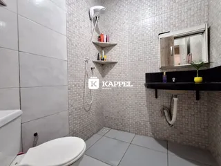 Foto interna de um banheiro com revestimento de azulejos brancos e bancada escura.