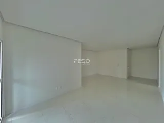 Ambiente interno de uma sala ampla com paredes brancas e piso claro.