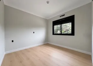Ambiente interno com paredes brancas e piso de madeira clara.