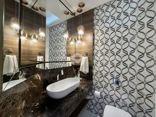Banheiro moderno com revestimento de mármore e iluminação decorativa.