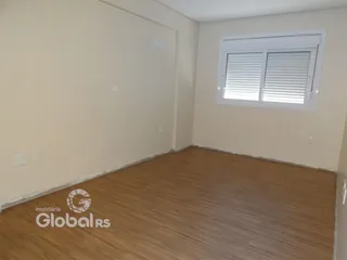 Quarto vazio com piso de madeira e janela de persiana.
