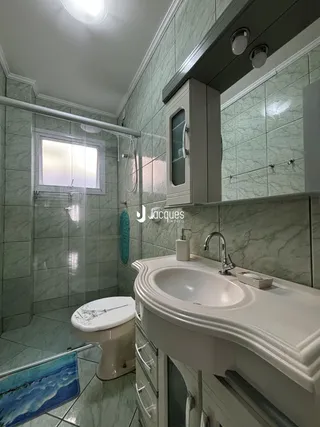 Foto de um banheiro com revestimento de azulejos verdes e louças brancas.