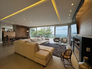 Sala de estar moderna com sofá grande e vista panorâmica da paisagem urbana.