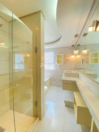 Banheiro com box de vidro e piso cerâmico claro.